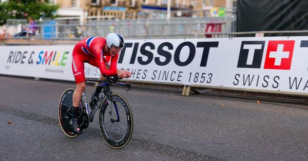 Cyclist in red competing in a race in Harrogate, England, showcasing speed and determination.