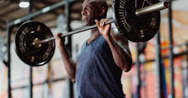 A focused man lifting weights in a gym setting, demonstrating strength and fitness.