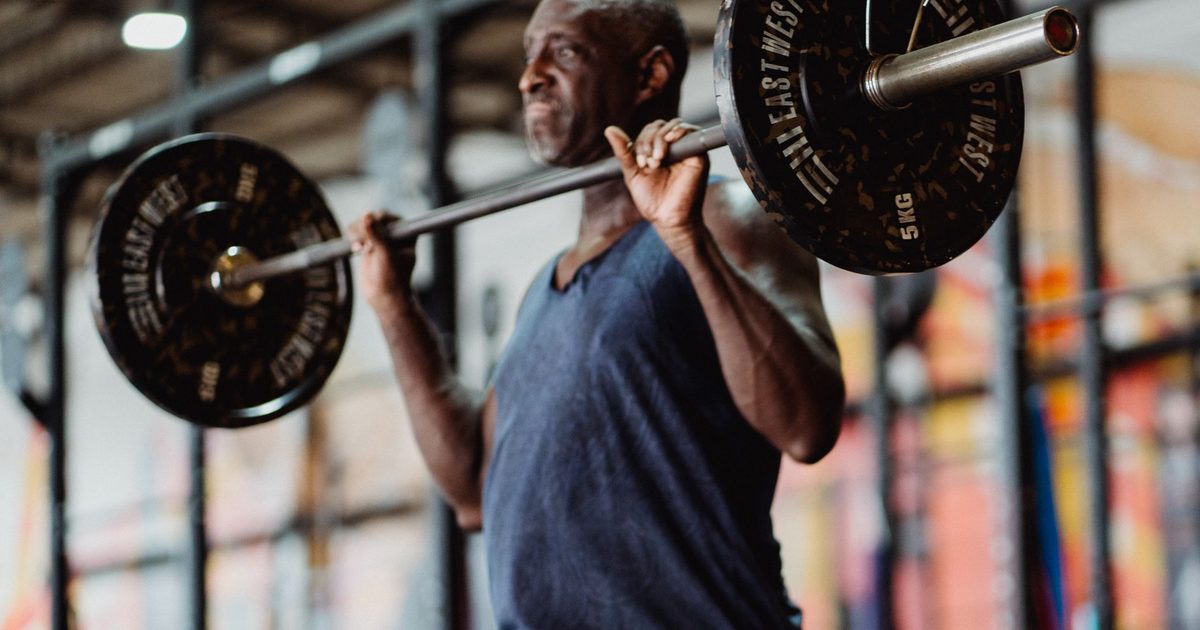 A focused man lifting weights in a gym setting, demonstrating strength and fitness.