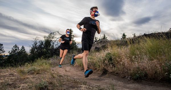 Athletes in VO2 masks running on a trail, showcasing outdoor athletic performance.