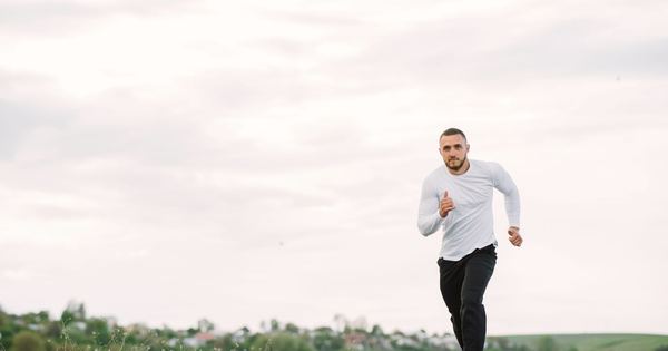 Adult man running on an empty road in casual sportswear, showcasing fitness and healthy lifestyle.