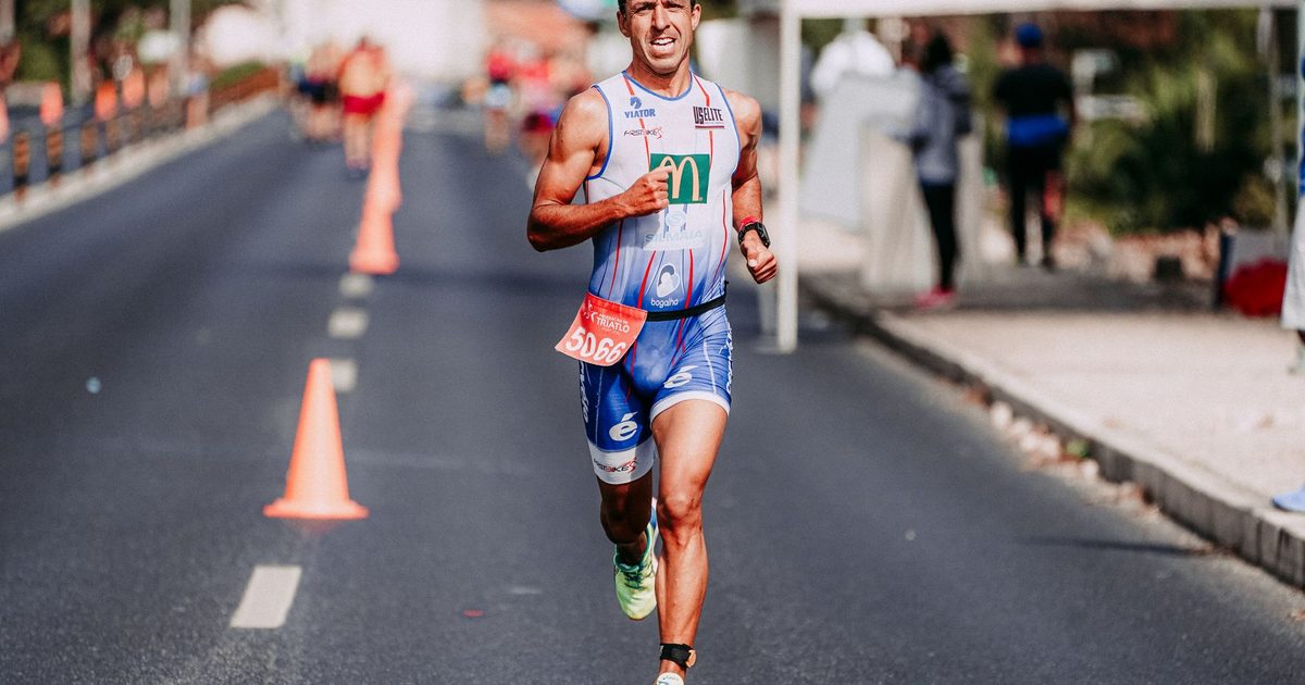 Full body of focused man in sportswear running fast on track during competition