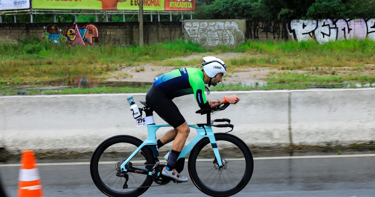 Professional cyclist competes in a race on a rainy day, wearing a helmet and racing gear.
