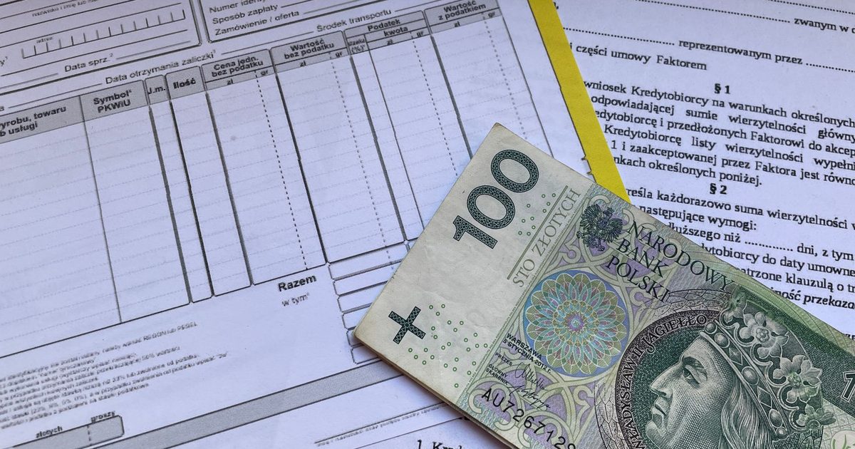 100 Polish zloty bill on top of financial documents and invoices on desk.