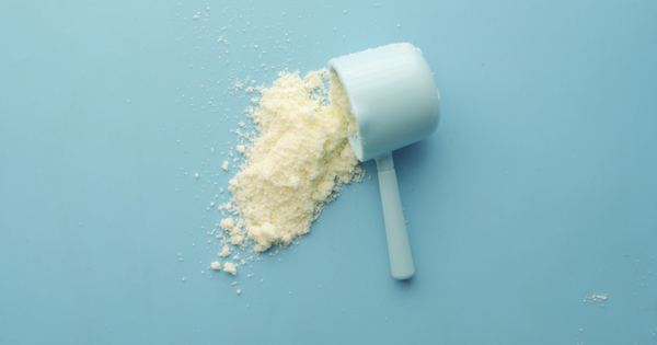 White powder spilled from a scoop on bright blue background. Clean and minimalistic food photo.