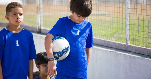 A group of boys in blue uniforms preparing for a soccer game outdoors.