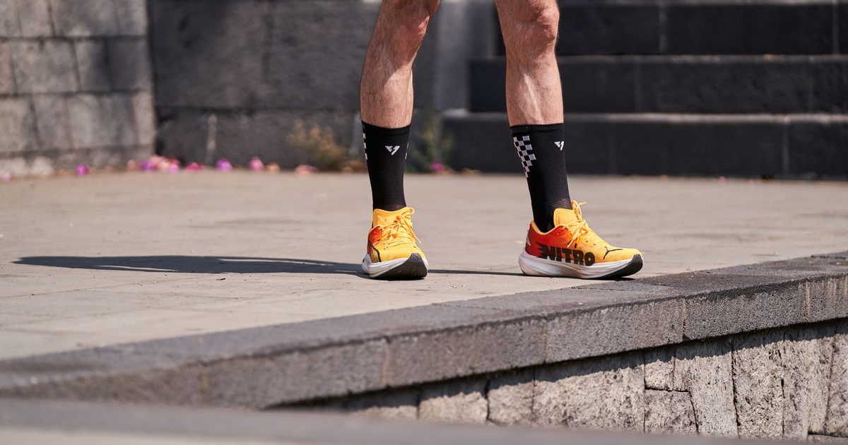 Close-up shot of a runner's legs wearing bright orange shoes and black socks.