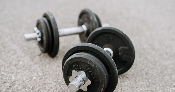 Massive metal dumbbells prepared for difficult healthy training on asphalt road in summer