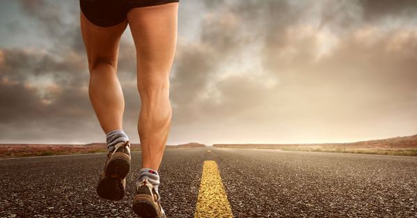 Runner's legs on a road during a sunset, symbolizing endurance and outdoor fitness training.