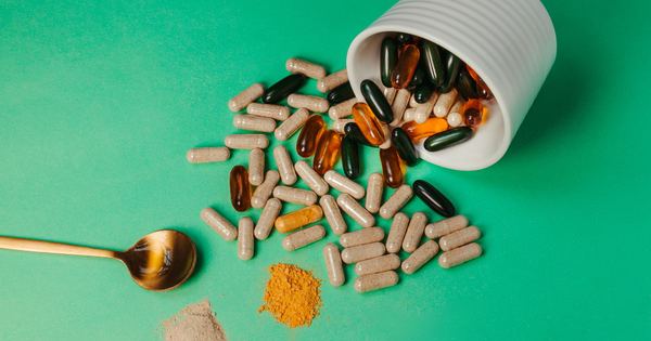 A mix of capsules, pills, and powder on green background with spoon.