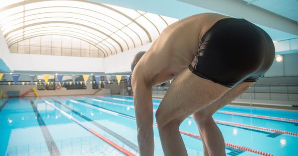An athlete in swimwear gets ready to dive into a competitive indoor pool.