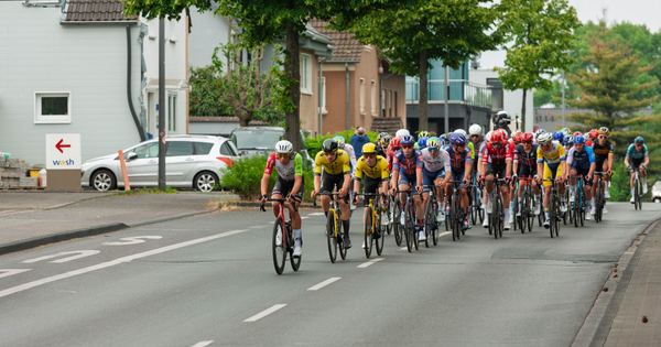 Cyclists in a high-speed competition racing through an urban area, showcasing athletic endurance and team strategies.