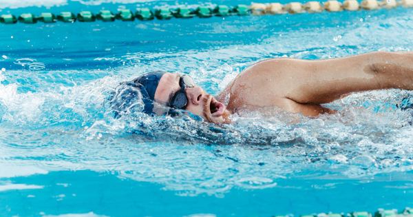A focused swimmer training in an outdoor pool, showcasing freestyle swimming technique.
