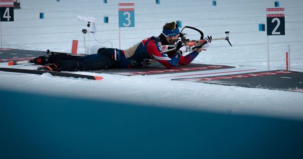 Biathlete competes in a snowy biathlon event, aiming with precision and focus.